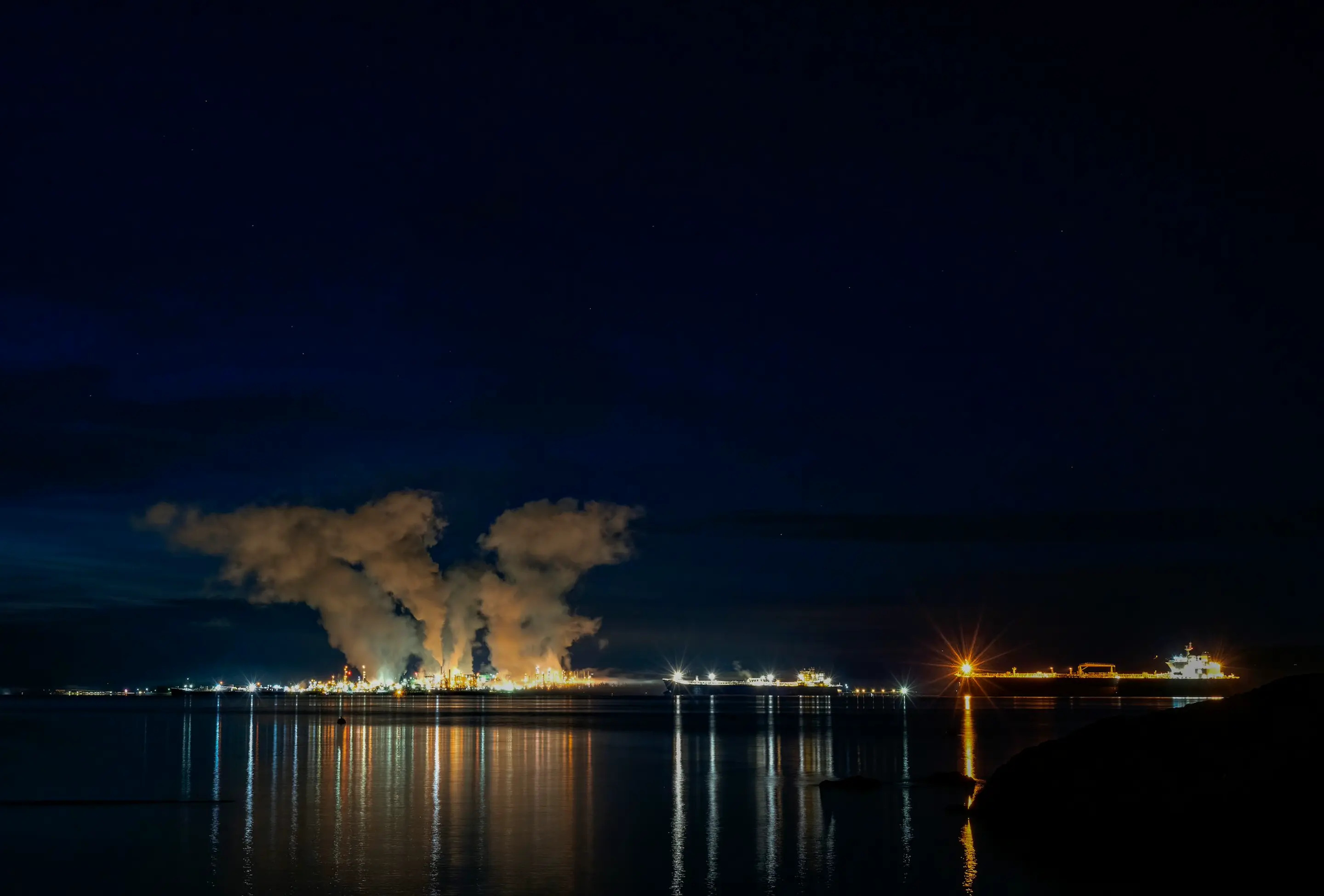 Night view of an energy terminal with golden lights on water